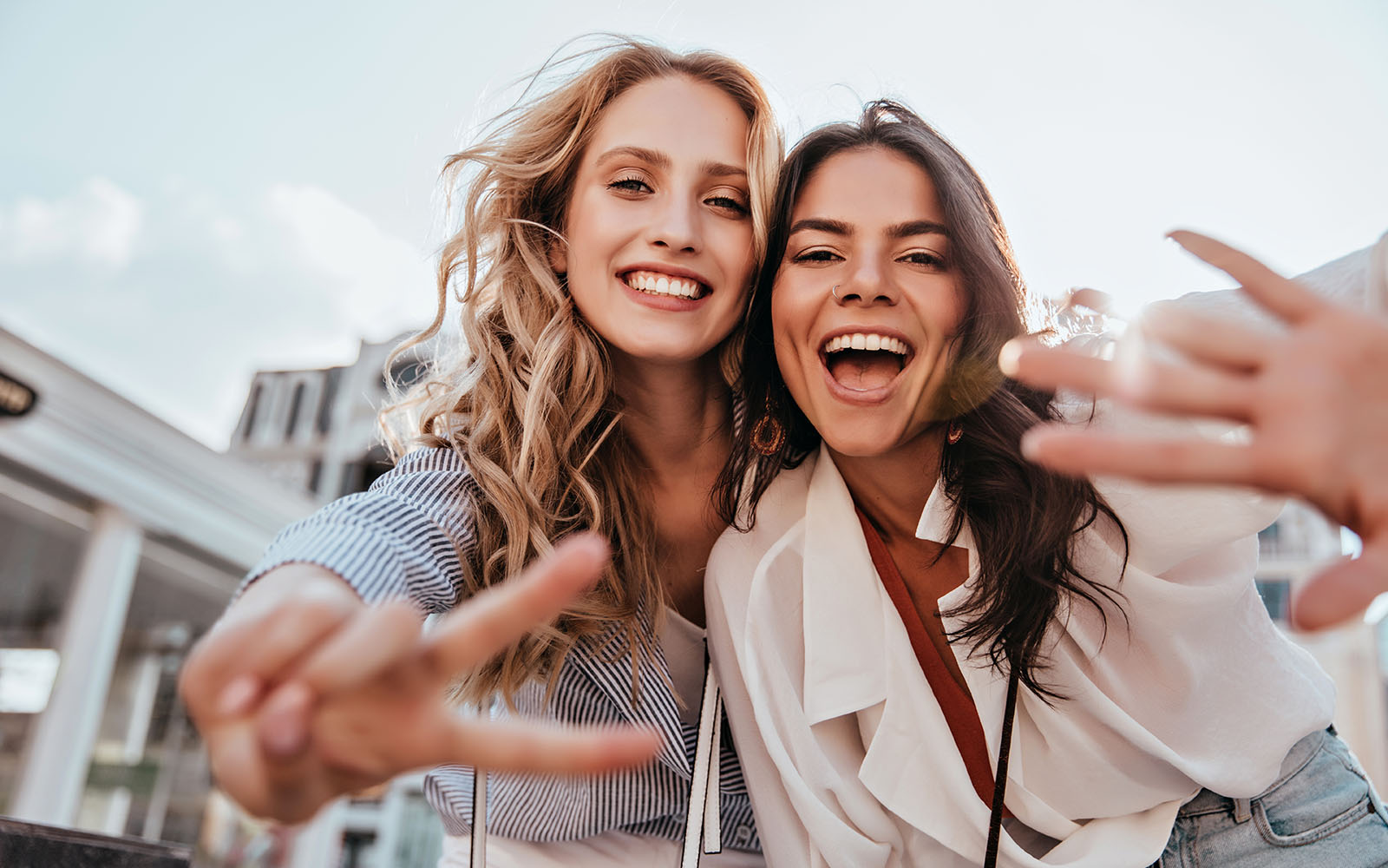 Two women taking a selfie with a cityscape in the background.