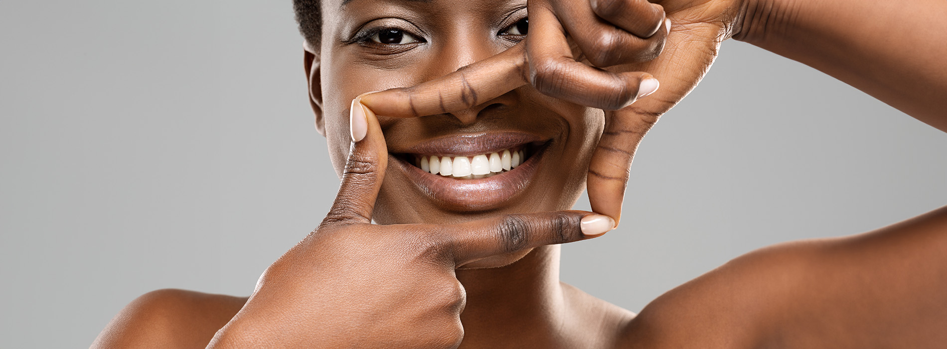 The image features a woman with her hands covering her face, making an obscuring gesture over her eyes, against a plain background.