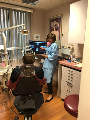 A dental professional demonstrating dental equipment to a patient.