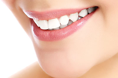 The image shows a close-up view of a person s face with a focus on their teeth, which are being highlighted by a bright smile.