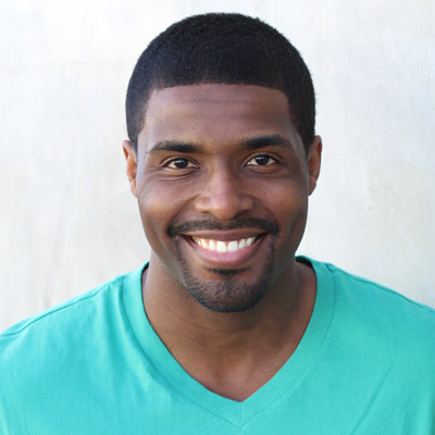 An elderly couple embracing each other with smiles on their faces, posing for a photo outdoors during daylight.