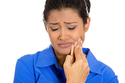A woman with her hand on her face, possibly expressing concern or worry, while looking at her hand which appears to be injured or in pain.